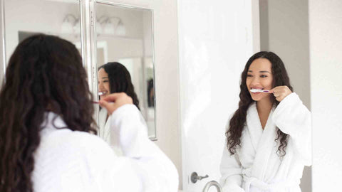 a woman brushing her teeth in front of a mirror