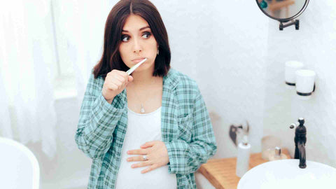 A pregnant woman brushing her teeth