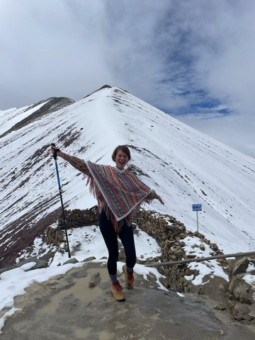 Ashley standing alone in front of Rainbow Mountain in Peru