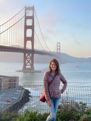 Ashley standing in front of the Golden Gate Bridge at sunset in San Francisco, California