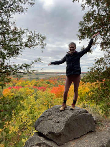 Standing on a boulder overlooking the viewpoint at Rattlesnake Point Conservation Area in Canada