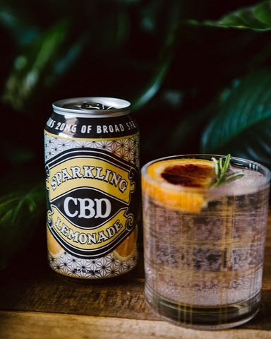 Sparkling CBD Lemonade can beside CBD cocktail in Collin's glass with mint and citrus garnish