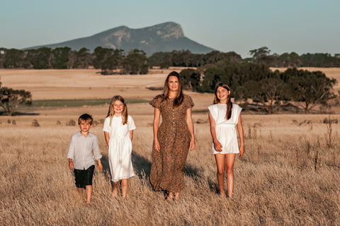 Amanda and her children standing in a paddock with the Grampians mountains in the background