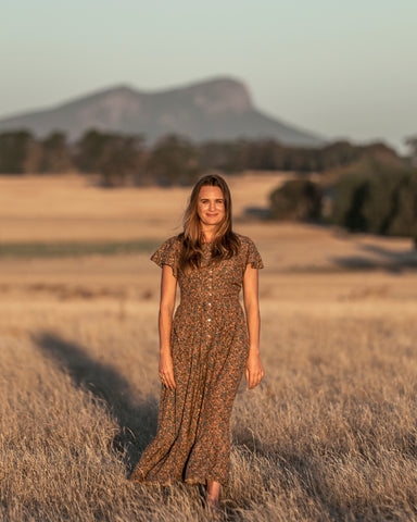Image of Amanda standing in a paddock with shadows behind her and the Grampians mountains in the distance