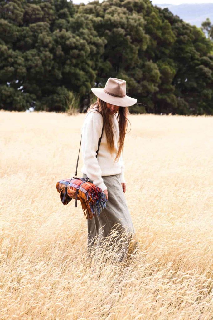 sarah glover walking in field with GGco. picnic blanket