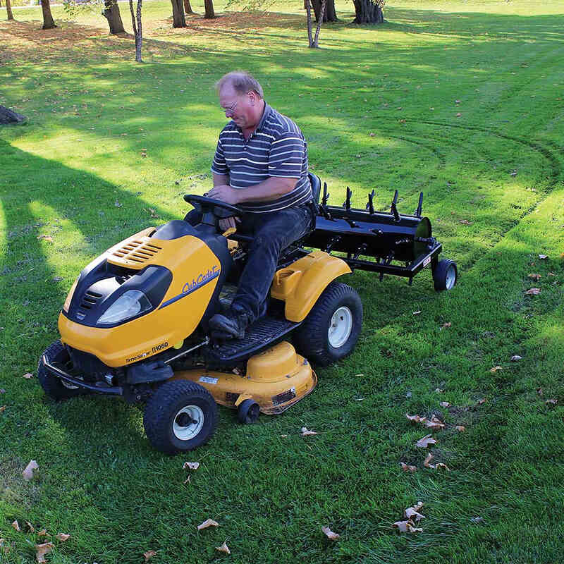 man riding his cub cadet mower with  Maxim tow behind aerator on the back