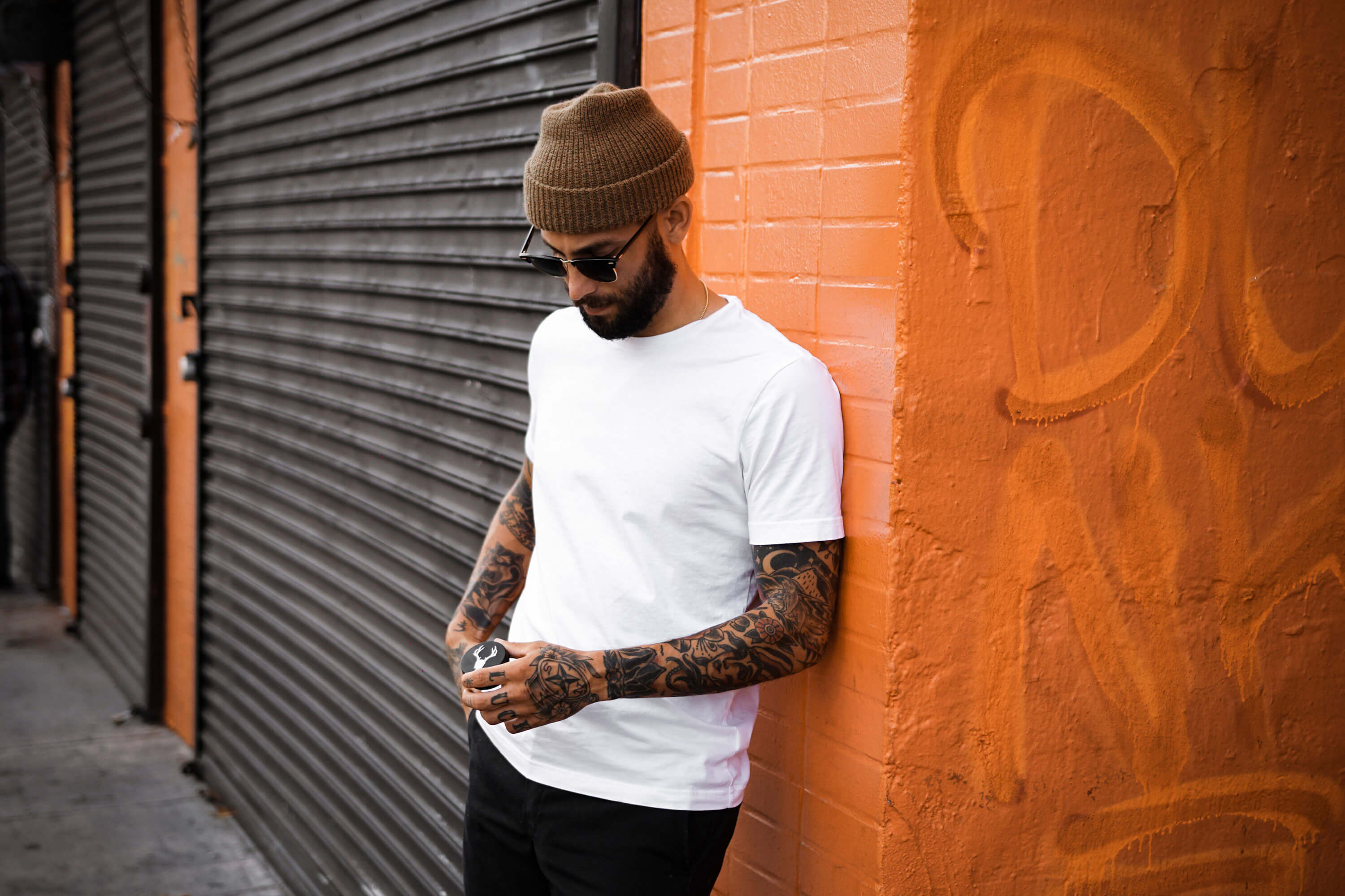 Man in white t-shirt leaning against wall