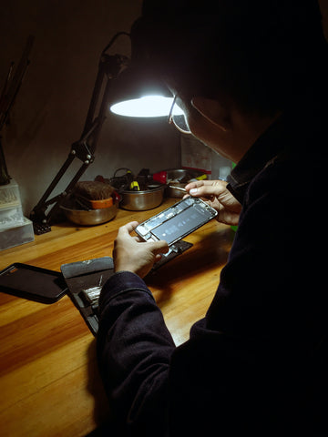 person working on their iPhone with the back open inspecting the phones battery