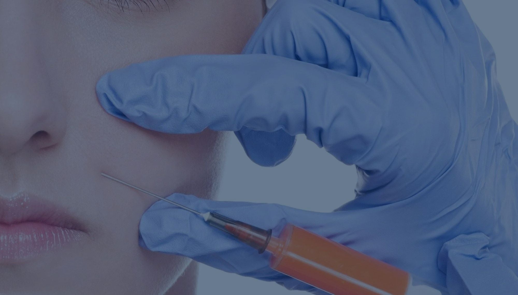 A close up of a womans cheek with a hand in a medical glove holding a needle to her skin.