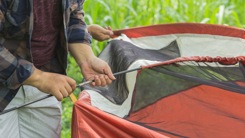 Guide for setting up a tent, person holding a tent pole