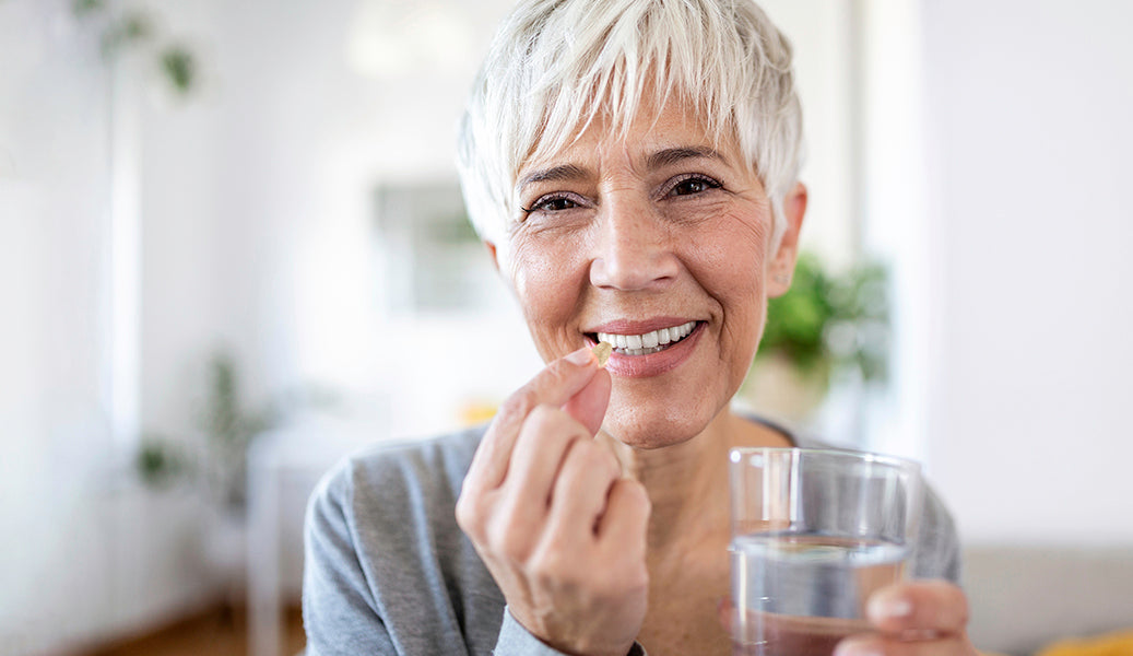 mature woman taking a kidney formula tablet