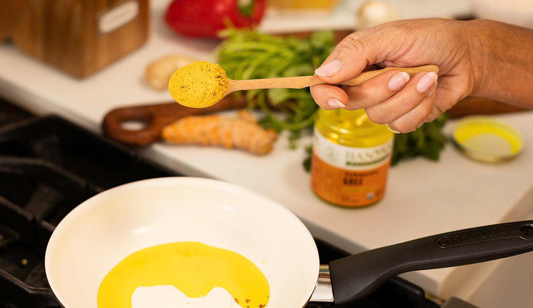 woman holding kitchari spice mix while cooking