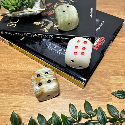 A stack of books that has an three onyx dice featured on top