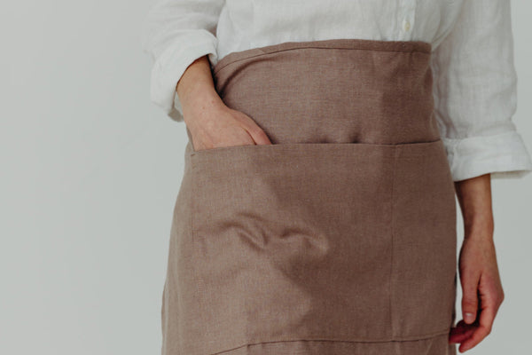 Close-up of half apron with hands in pockets