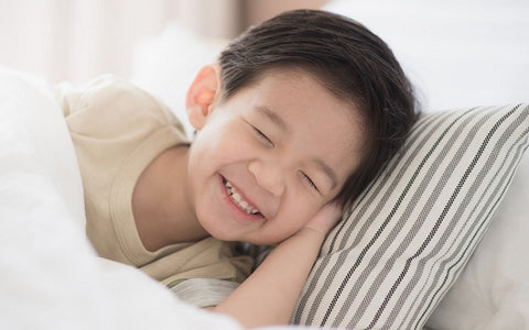 Grinning toddler boy on A Little Pillow Company pillow