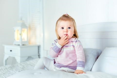 Toddler on bed with A Little Pillow Company pillows