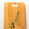 A beach wood chopping board, wood-burnt with design of a dragonfly landing on a stalk. Finished with acrylics.