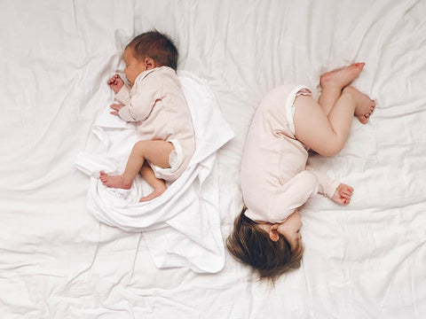 two babies sleeping on the bed in tandem position