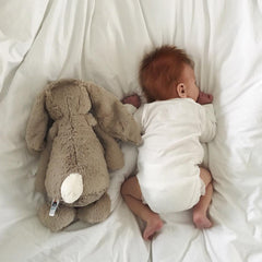 baby with rabbit teddy on bed