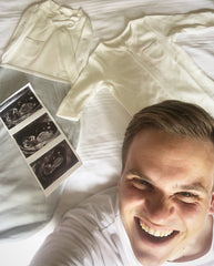 dad to be with baby clothes and scan