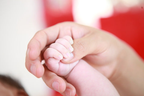 dad holding a new baby's hand