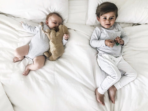 Baby siblings on a bed sleeping