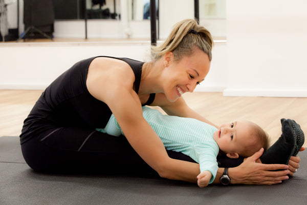Mother with her baby doing yoga stretching 