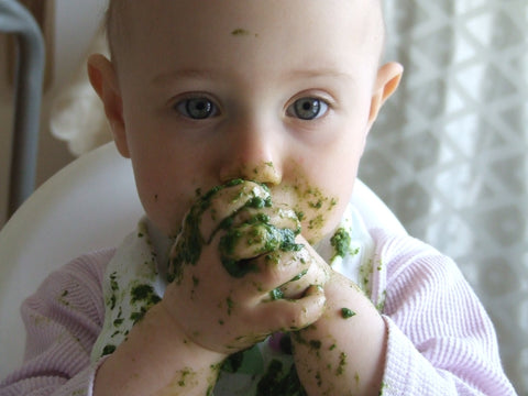 baby eating green vegetables