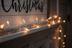 lighted rope garland laying on mantle at christmas