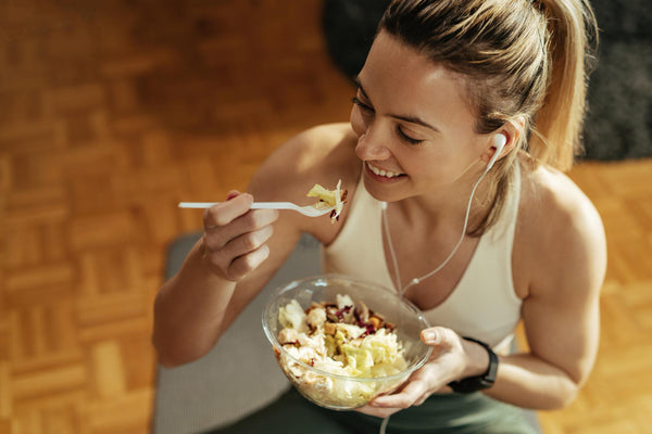 Image of woman enjoying healthy salad with grilled chicken after home training