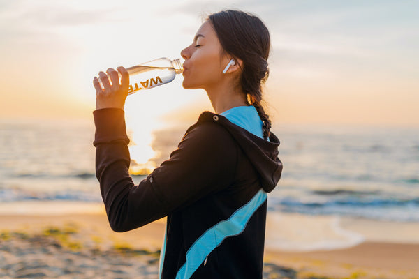 Image of woman drinking water to stay hydrated during workout