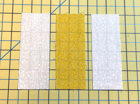 Three strips of fabric laying side by side for testing an accurate quarter inch seam for quilt piecing.