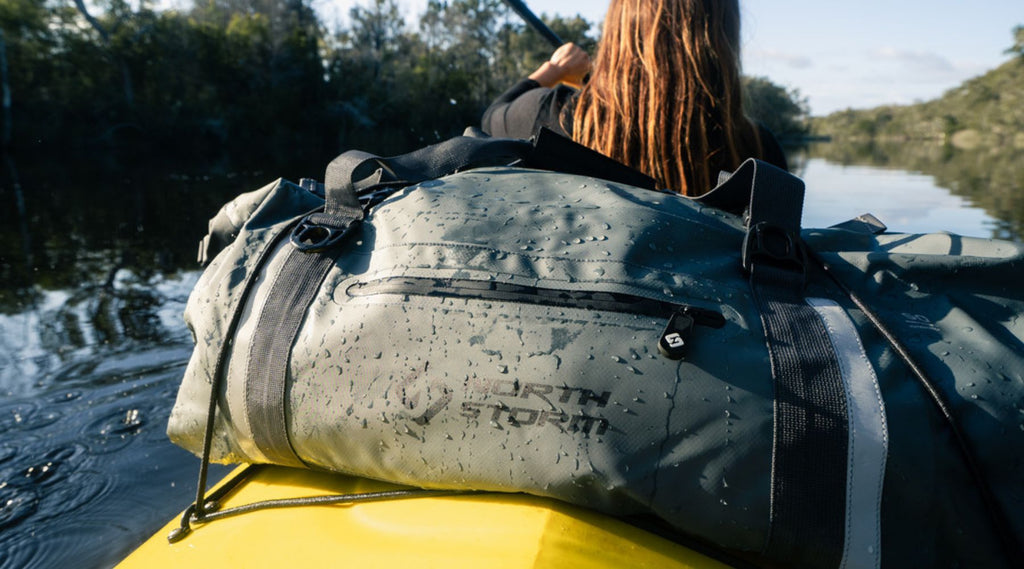 A lady paddling a kayak with a North Storm 60 litre duffel bag behind her.