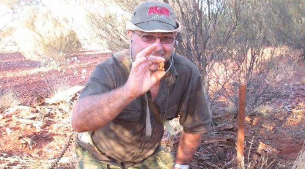 A man standing in the outback of Western Australia holding a huge Gold Nugget he just found. He is very happy. 