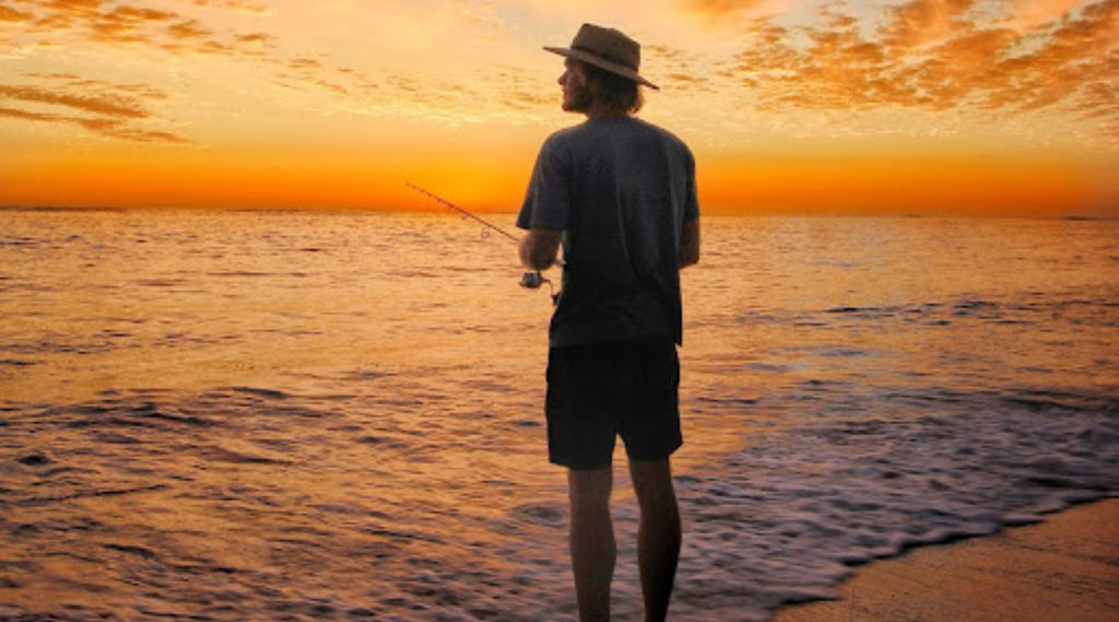 A MAN FISHING AT SUNSET AT CORONATION BEACH CAMPGROUND, WESTERN AUSTRALIA, AUSTRALIA.