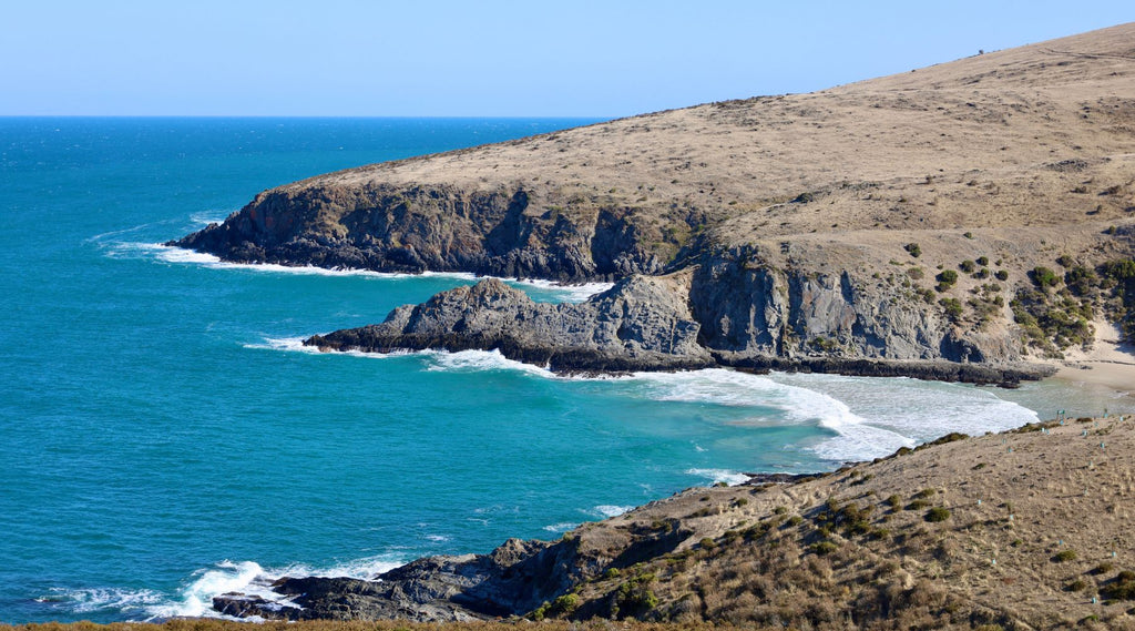 The rugged coastline of the fluerieu peninsula meeting the ocean.