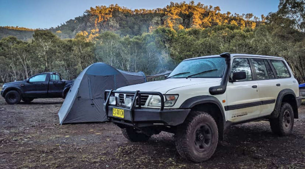 Two four wheel drives and a tent camping.