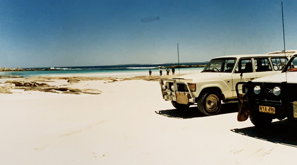 Two, four wheel drives parked on a beach.
