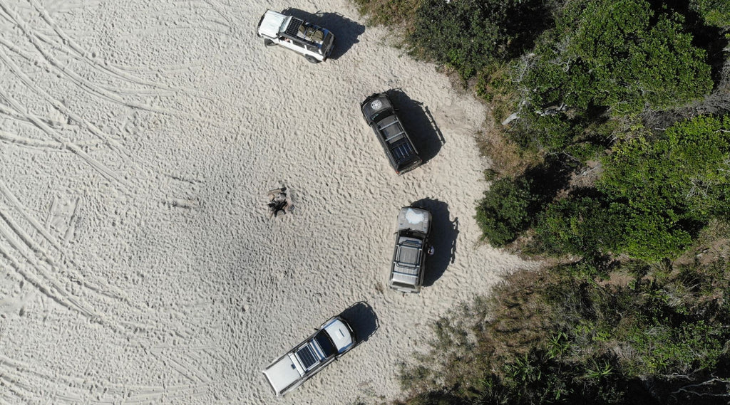 FOUR 4X4'S PARKED ON A BEACH.