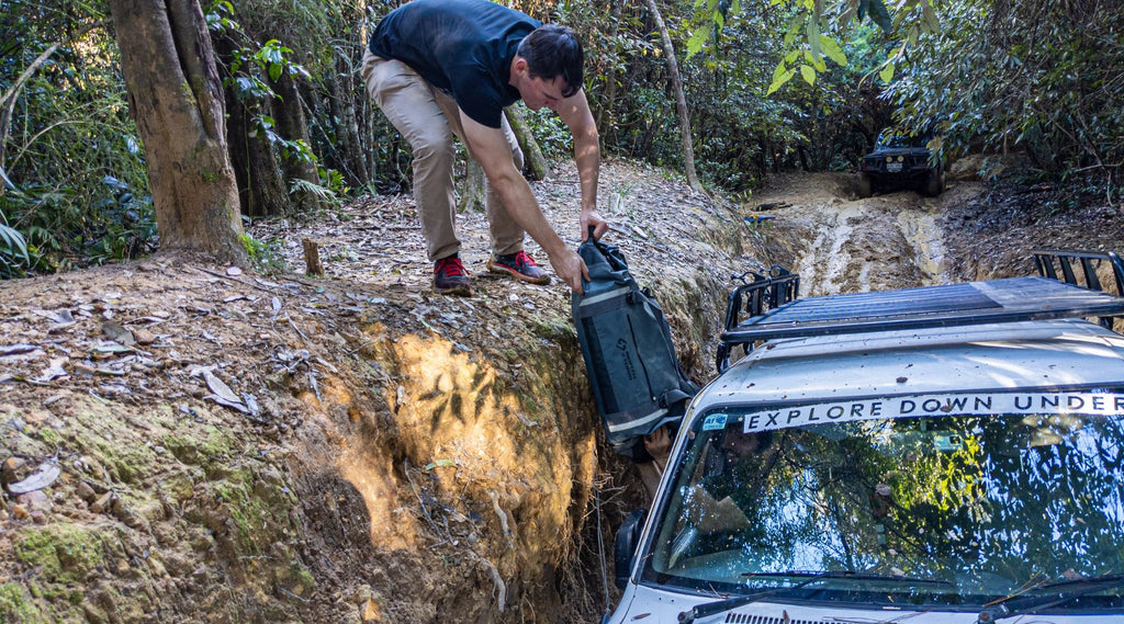 EXPLORE DOWN UNDER GETTING A NORTH STORM DUFFEL BAG PASSED THROUGH THE WINDOW OF A 4 WHEEL DRIVE.
