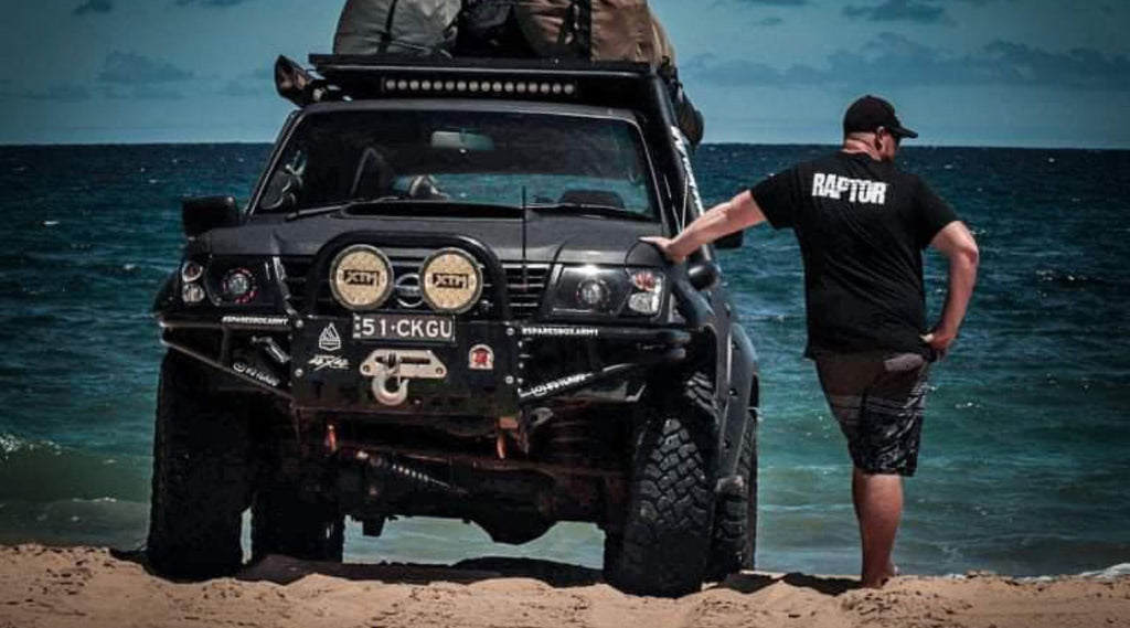 GAZ NORTH STORM AMBASSADOR STANDING ON BEACH LEANING AGAINST HIS 4 WHEEL DRIVE.