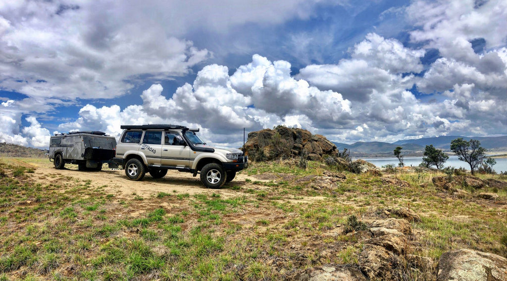 WOOLGOOLGA OFFROAD'S LANDCRUISER PARKED TOWING A CAMPER TRAILER ON A CLOUDY DAY.