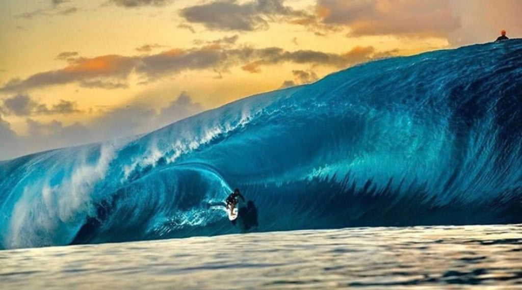 SURFER SURFING A HUGE WAVE THAT IS CURLING OVER THE TOP OF HIM.