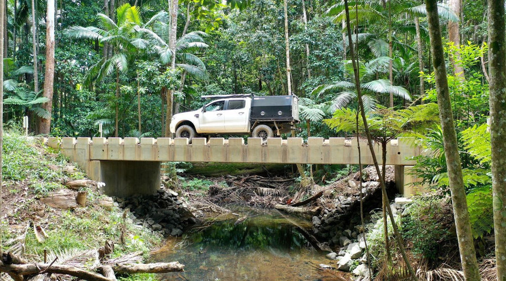 BIG OZ EXPLORERS DRIVING OVER A BRIDGE IN THE FOREST.