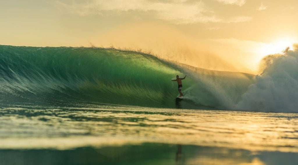 A MAN SURFING A ROLLING WAVE.