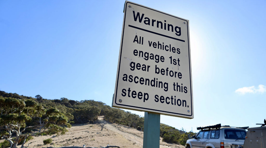 A sign that says: All vehicles engage 1st gear before ascending this steep section.