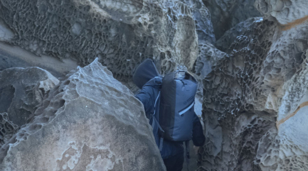 A man exploring through rocks with a North Storm 30 Litre waterproof backpack on.