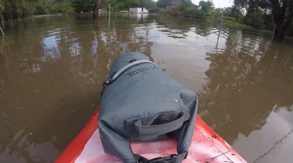 A North Storm 20 litre dry bag in a kayak floating through flood waters. 