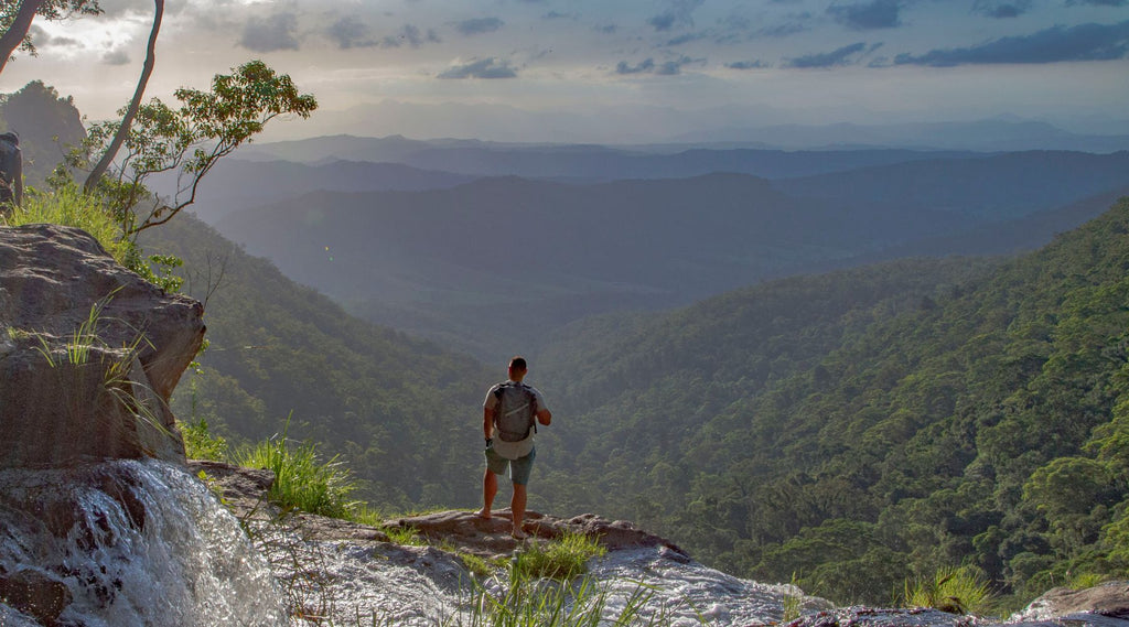 A man standing on a cliff looking out over beautiful scenic mountain ranges wearing a North Storm 30 Litre Backpack.