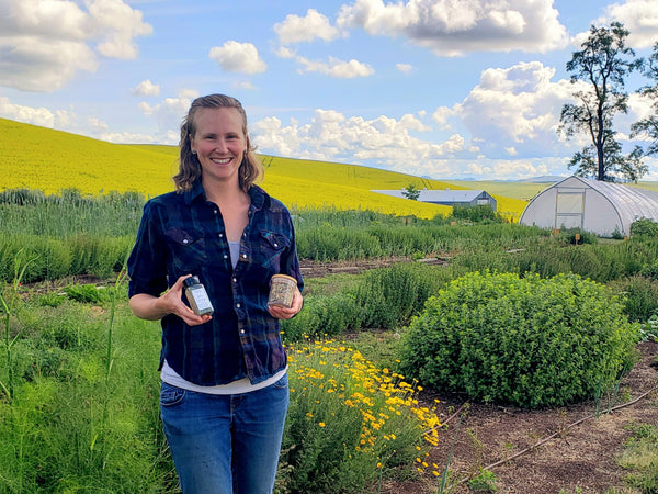 Lindsay Myron holding her dried tea and seasoning products in the field at Smoot's Flavor Farm